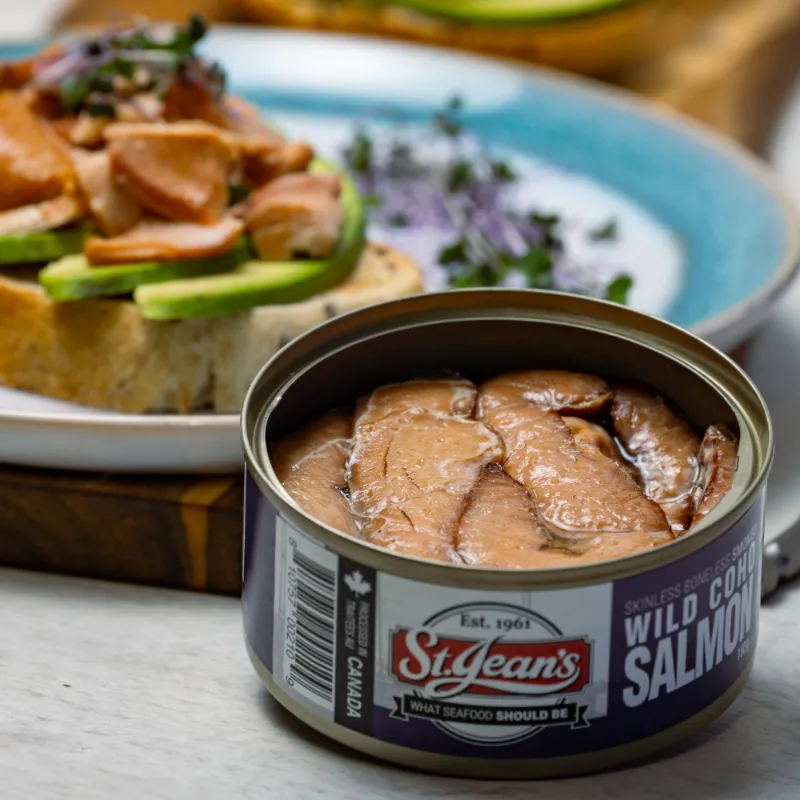 front view of canned smoked wild coho salmon with an open faced sandwich in the background