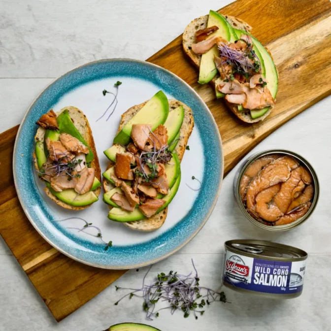 top view of canned wild smoked coho salmon with avocado on toast and an open can showing the smoked coho inside